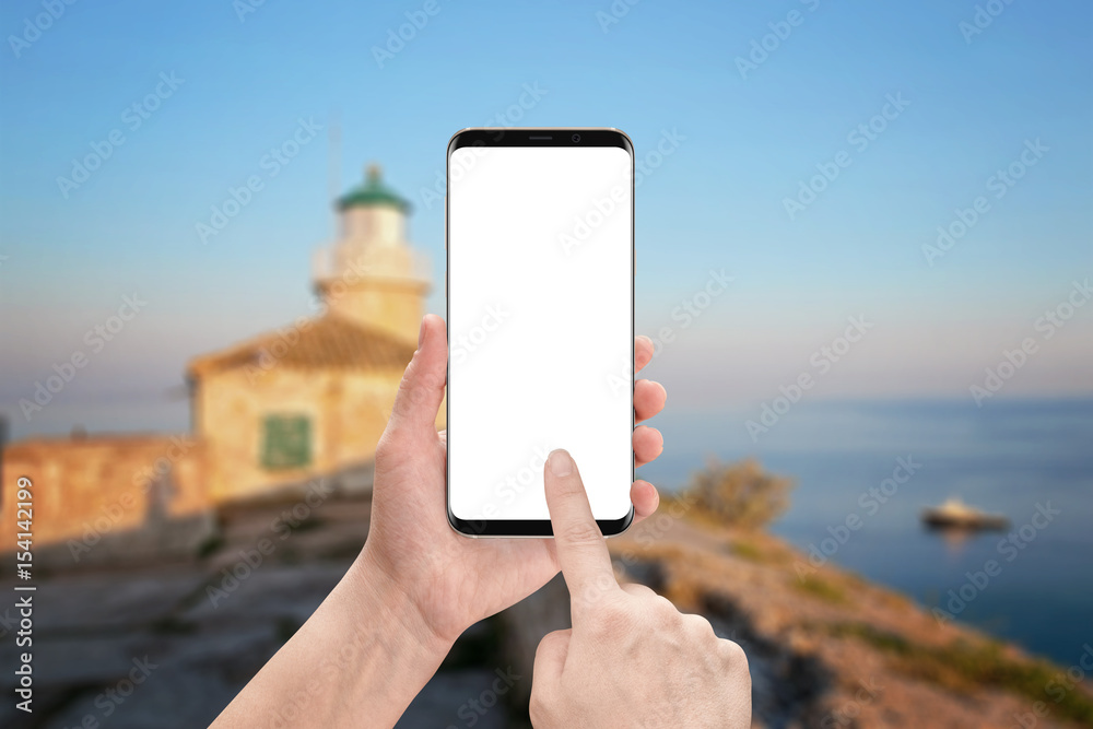 Poster Woman touch modern smart phone screen. Isolated display for mockup with round edges. Lighthouse and sea in background.