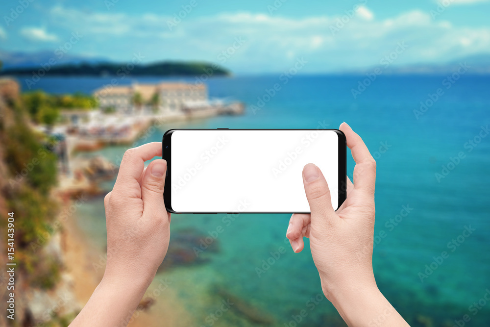 Poster woman play game or use app on mobile phone with isolated white screen. coast and sea in background.