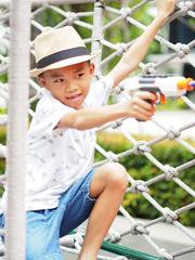 Asian boy is shooting a toy gun.