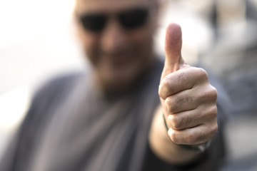 Caucasian man with sunglasses making ok sign at camera. Selective focus on foreground