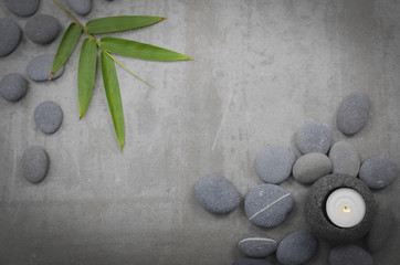 Fototapeta na wymiar bamboo leaf, with pile of gray stones, with candle -gray background