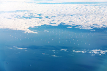 Fototapeta na wymiar Offshore windpark in blue ocean with white clouds