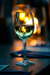 Green glass of water is on the table in a dark restaurant.