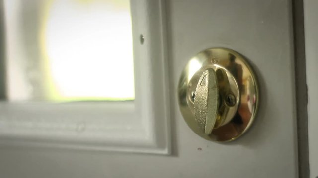Multipurpose clip - Man locks and unlocks his double gold deadbolt lock on modern door