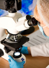 Laboratory assistant or technician in medical research lab looking into a microscope and doing research