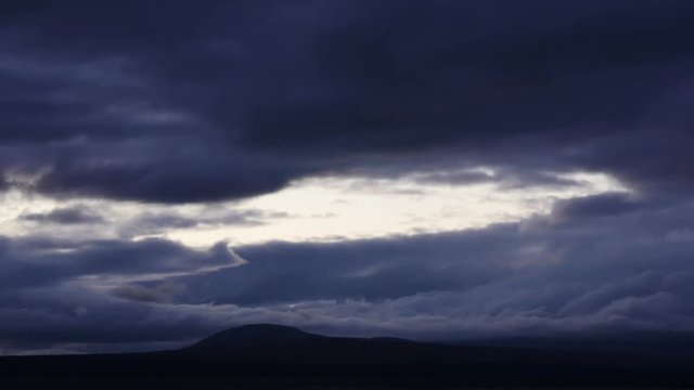 Time lapse of dark dramatic clouds moving over hills at sunset, Norway
