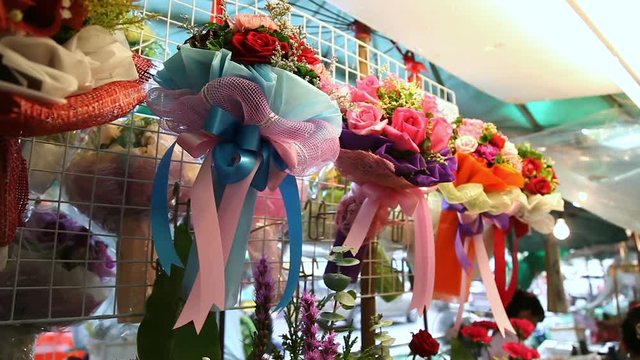 Showcase with bouquets on flower market. Cutted roses decorated with colored paper, sisal and ribbons. Bangkok, Thailand.