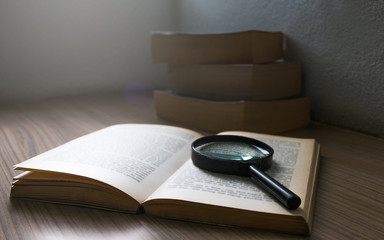 Magnification glass over a opened book in the dark room