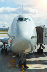 Fototapeta na wymiar Jumbo Plane Head. Big passenger plane at gate at the airport front view. Sunny cloudy day.