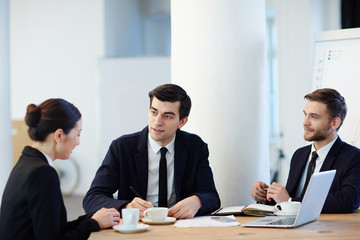 Young specialist answering questions of two employers during interview
