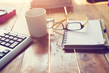 Notebook or note pad,smart phone,cup of coffee and glasses on wooden background with copy space. office desk concept
