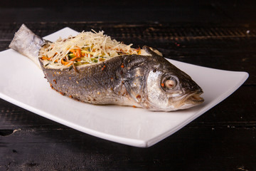 Fish with filling, stuffed with vegetables and cheese on white plate. Close-up