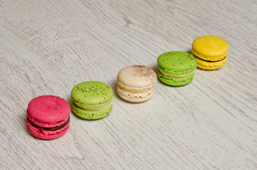 Five macaroni of different colors on a light wooden table