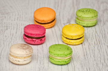 Six multicolored macarons on a light wooden table