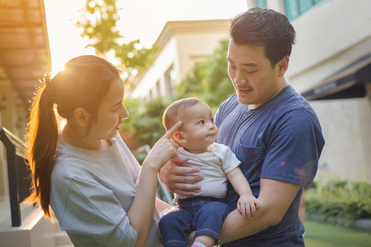 Happy Asian baby with his mother and father playing together in the park