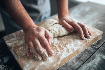 Baker hands kneading the dough with flour