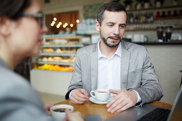 Two modern traders discussing online data while sitting in cafe