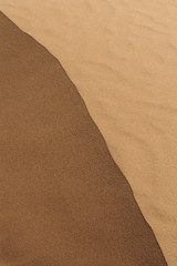 top of sand dune lit from one side by sun