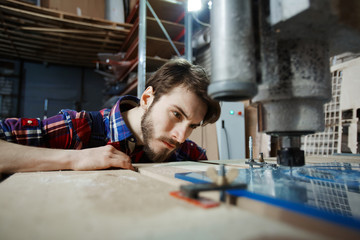 Portrait of handsome young engineer operating glass cutting machine, watching engraving process...