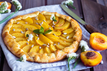 Homemade galette with nectarine peach on rustic wooden background. Top view, Horizontal