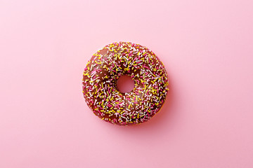 Donut isolated on a pink background. A single doughnut with chocolate icing. Top view