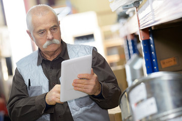 Senior man using tablet at work - obrazy, fototapety, plakaty
