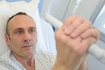 Patient in hospital bed gripping hoist