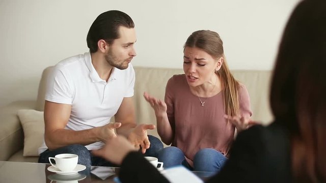 Family facing relationship difficulties. Young couple visiting professional psychotherapist office, fighting with each other at therapy session. Marriage counselor stopping quarrel with hand gesture
