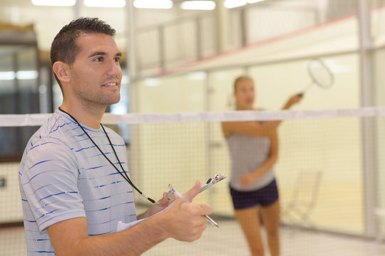 teacher giving attractive woman badminton lesson