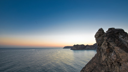 Orange glow of dawn across a calm blue ocean