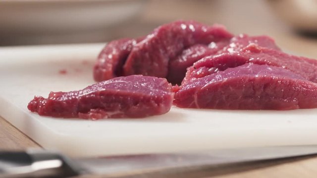 Slide shot of young female hand taking raw beef with from plastic board, 180fps prores footage