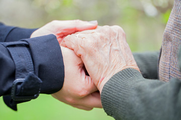 Senior & young woman holding hands