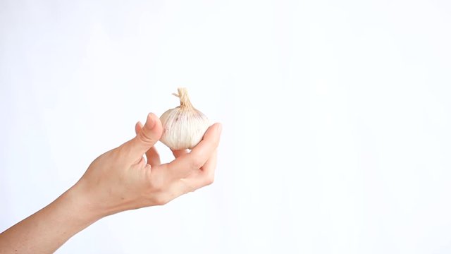Female hand holding garlic on white background