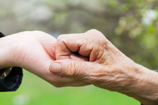Senior & young woman holding hands