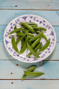 Sugar snap peas on blue wooden background.