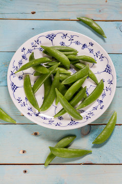 Sugar snap peas on blue wooden background.