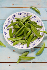 Sugar snap peas on blue wooden background.