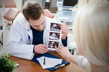 Doctor showing baby ultrasound image to pregnant woman