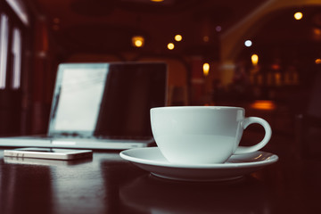 cup of coffee on old wooden desk. Simple workspace or coffee break in morning/ selective focus