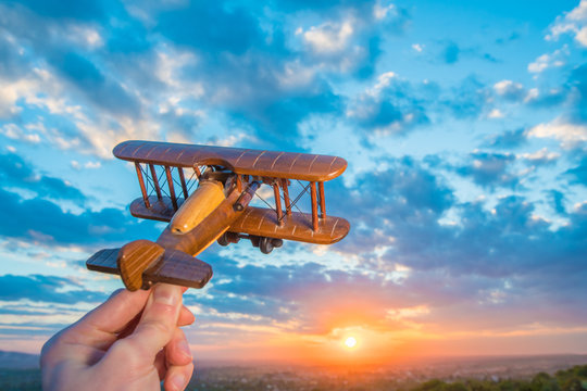 The hand with a toy airplane on the background of a sunset