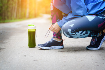 Female runner tying shoe lace in the park.