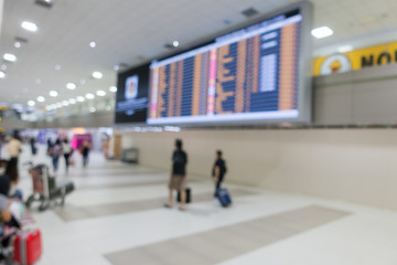 Blurred background of people traveling in Airport with departure board.