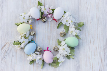 round of easter pastel painted eggs and quail eggs on light wooden background