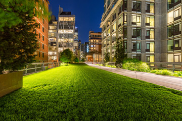 Highline promenade and lawn at twilight with city lights in the heart of Chelsea. Manhattan, New York City