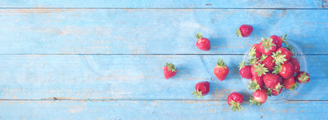 red wild strawberries on old blue wooden table, flat lay,  good copy space