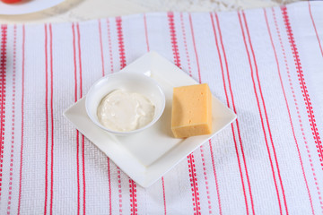 Sour cream and cheese on a white plate on a white background