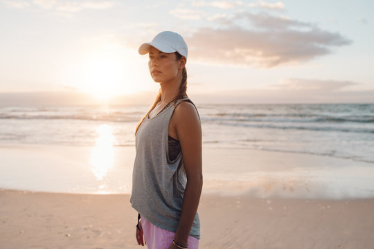 Fit young woman in sportswear standing on the beach