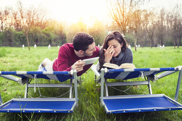 nice couple relax on deckchair reading book and tablet