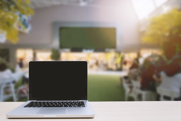Fototapeta premium blank screen laptop on wooden table with out door or co work scape blurred background and sunlight for technology 4.0; digital life concept.