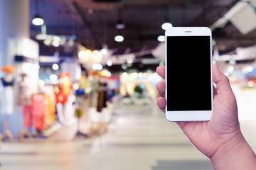 Man holding blank screen smartphone with blurred shopping mall background for technology 4.0; digital life; shopping online; payment concept